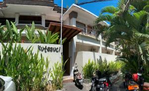 a house with motorcycles parked in front of it at Kuta Suci Guesthouse in Kuta