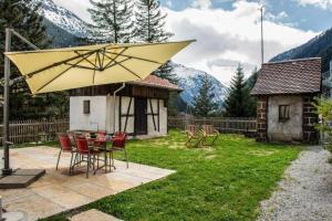 eine Terrasse mit einem Tisch und einem großen gelben Sonnenschirm in der Unterkunft Bahnwärterhaus Eggwald - b48797 in Wassen