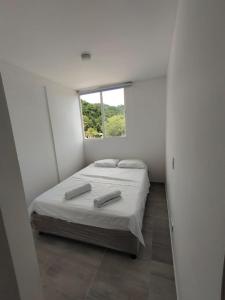 a white bedroom with a bed and a window at Apartamento en entorno natural in Villeta