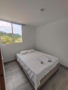 a white bedroom with a bed with a window at Apartamento en entorno natural in Villeta +21 photos