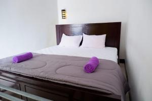 Una cama con dos almohadas moradas encima. en Family Guest House Moni en Kelimutu