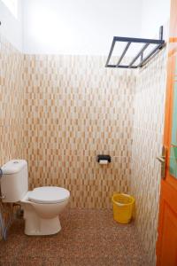 a bathroom with a toilet in a tiled wall at Family Guest House Moni in Kelimutu