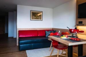 ein Wohnzimmer mit einem roten Sofa und einem Tisch in der Unterkunft Chalet Raufthubel 2-Zi Apartment - b48763 in Mürren