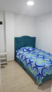 Cama en habitación con edredón azul en Apartamento turístico portal del prado, en Santa Rosa de Cabal