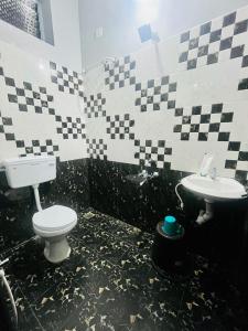 a black and white bathroom with a toilet and sink at Bay Walk Residency in Auroville