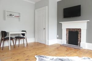 a living room with a fireplace and a table and a television at Historic Downtown Apt #2 in Halifax