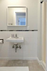 a white bathroom with a sink and a mirror at Historic Downtown Apt #2 in Halifax