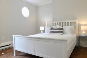 a white bedroom with a white bed with two lamps at Historic Downtown Apt #2 in Halifax