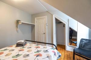 a bedroom with a bed and a black chair at Sunny Loft #4, Historic Home in Halifax