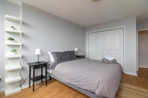 ein weißes Schlafzimmer mit einem Bett und einem Tisch mit einer Lampe in der Unterkunft Bright & Spacious 2-BDRM Apt #6A, Patio in Halifax