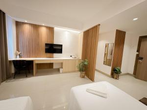 a hotel room with a bed and a desk with a television at LEUX Hotel Alona Panglao in Panglao Island