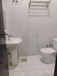 a white bathroom with a toilet and a sink at Dorar Rabigh Complex Residential Units in Rabigh