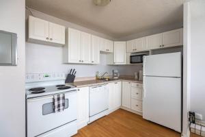 a kitchen with white cabinets and a white refrigerator at Bright DT Apt #7A, Amazing View in Halifax