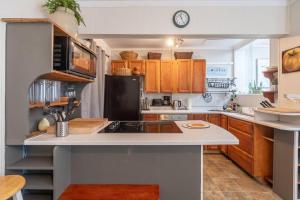 a kitchen with wooden cabinets and a black refrigerator at Charming Townhouse, Historic Hydrostone in Halifax