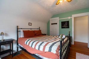 a bedroom with a bed with orange pillows and green walls at Charming Townhouse, Historic Hydrostone in Halifax