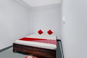 a bed with red pillows in a white room at OYO Flagship YUVRAJ Hotel in Patna