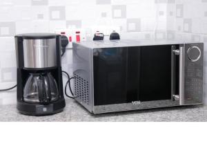 a microwave sitting on a counter next to a coffee maker at 3 BEDROOM LIWANDO HOME at Greatwall Gardens next to Greatwall Mall, 15 Minutes from JKIA Airport With FREE WIFI & Parking, Enjoy Entire Unit in a Gated Community manned with Security 24 Hours in Athi River
