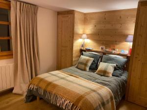 een slaapkamer met een bed met een houten muur bij Chalet Méribel, 4 pièces, 8 personnes - FR-1-688-73 in Méribel