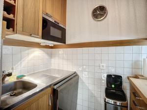 a small kitchen with a sink and a clock on the wall at Appartement Méribel, 2 pièces, 5 personnes - FR-1-688-75 in Méribel