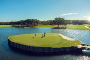 dos personas en un campo de golf junto a un cuerpo de agua en Evermore Orlando Resort, en Orlando