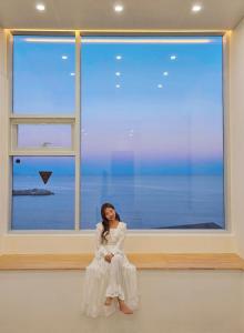 a woman in a white dress sitting in front of a window at OOU SPACE in Geoje