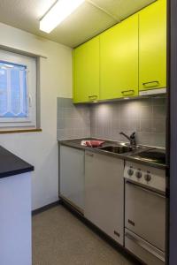 eine Küche mit gelben Schränken und einem Waschbecken in der Unterkunft Familienfreundliche Ferienwohnung mit Spielwiese Haus Reanchme Parterre - b48833 in Sörenberg