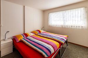 ein Schlafzimmer mit einem Bett mit einer bunten Decke darauf in der Unterkunft Familienfreundliche Ferienwohnung mit Spielwiese Haus Reanchme Parterre - b48833 in Sörenberg