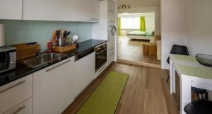 uma cozinha com armários brancos e um tapete verde em Moderne Landwohnung London im Thurgau - b48853 