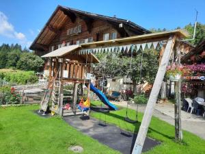 un parque infantil frente a una casa de madera en 45 Zimmer Ferienwohnung Hofstatthaus - b48818, en Hasliberg