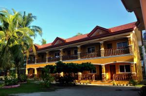 un grande edificio giallo con balcone e palme di SLAM'S Garden Dive Resort a Isola di Malapascua