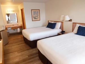 Habitación de hotel con 2 camas y espejo en Harbor Inn, en Brookings