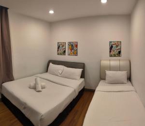 two beds in a room with white walls at Taragon Suits Apartment KL in Kuala Lumpur
