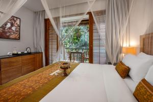 a bedroom with a large white bed and a window at Adiwana Svarga Loka - A Retreat Resort in Ubud