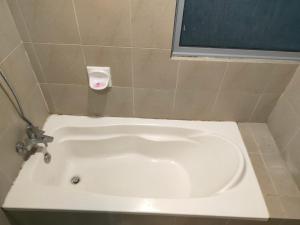 a white bath tub in a tiled bathroom at Taragon Suits Apartment KL in Kuala Lumpur