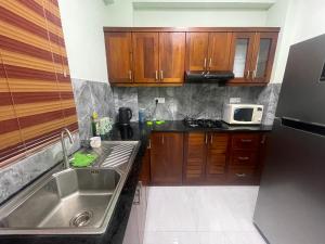 a kitchen with wooden cabinets and a sink and a microwave at Mount Apartment in Ratmalana North