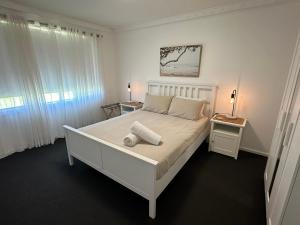 um quarto com uma cama branca e 2 janelas em Peppermint Cottage em Broadwater