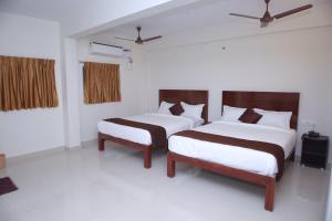 two beds in a room with white walls at Grand Pacific in Puducherry