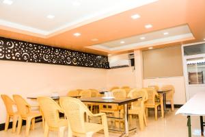 une salle à manger avec des tables, des chaises et un tableau noir dans l'établissement Viswa Service Apartment, à Madurai