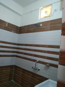 - une salle de bains avec des rayures brunes et blanches sur le mur dans l'établissement Haridwar and kedarnath dharmshala, à Haridwar