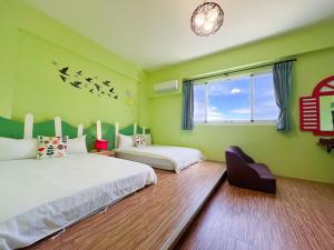 two beds in a room with green walls and a window at 艾希兒民宿 l小家庭可包棟 in Taitung City