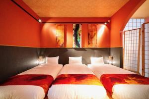 two beds in a room with orange walls at ゼロイン祇園三条 in Kyoto