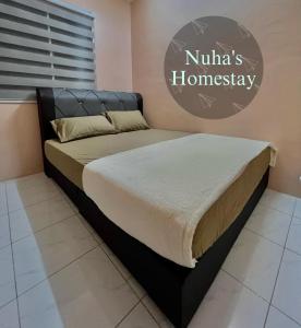 a bed in a bedroom with a sign on the wall at Nuha's Homestay Teluk Intan in Teluk Intan