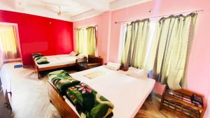 a bedroom with two beds and a red wall at Hotel Vishal in Siliguri
