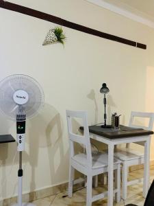 Zimmer mit einem Tisch, einem Ventilator und Stühlen in der Unterkunft Muggiez Olive, Kira in Kampala