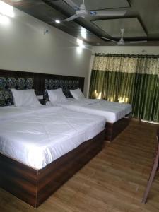 2 große Betten in einem Schlafzimmer mit Vorhängen in der Unterkunft Rishikesh by prithvi yatra hotels dharmshala in Rishikesh