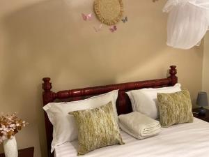 1 cama con almohadas blancas y mariposas en la pared en Muggiez Olive, Kira en Kampala