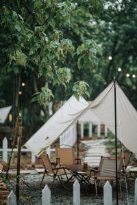 a group of chairs and a white tent at De Kampung Campsite in Rawang