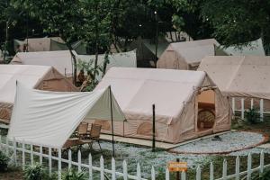 a group of tents behind a white fence at De Kampung Campsite in Rawang