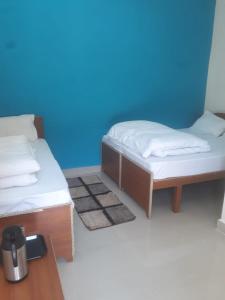 Rishikesh by prithvi yatra hotels dharmshala في ريشيكيش: سريرين في غرفة ذات جدار أزرق