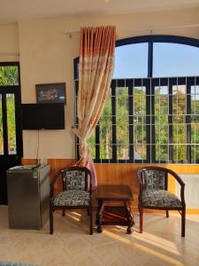 een woonkamer met 2 stoelen en een televisie bij Green Hill Guest House in Ba Hòn